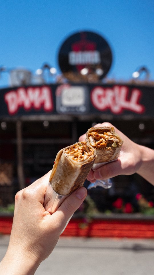 Dama Grill storefront in West LA with two shawarma wraps held up